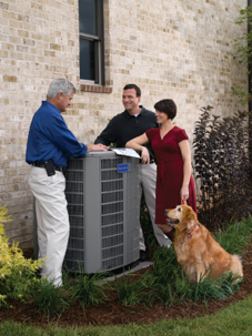 HVAC technician showing a new heat pump system to Cedar Park homeowners with their dog in the backyard