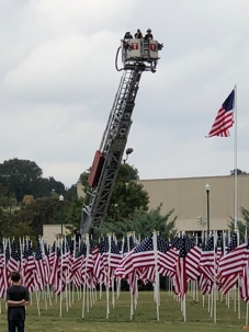 Firefighters raise an aerial ladder over hundreds of American flags at the Georgetown Field of Honor event in San Gabriel Park, Georgetown, Texas.