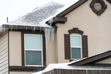 Icicles forming along a home’s roof and eaves, highlighting freeze conditions that can threaten HVAC systems, heat pumps, and exposed condensate lines during an Austin arctic front.