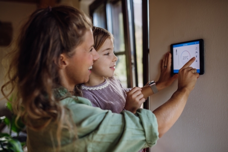 Mom and daughter adjusting smart thermostat