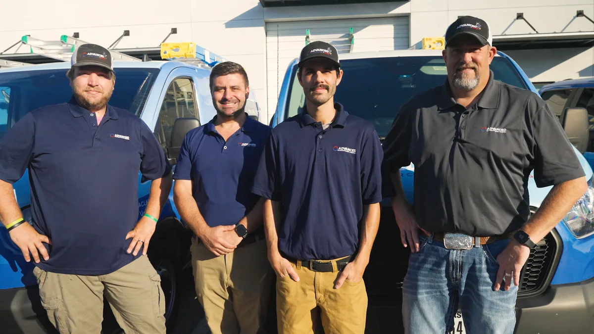 Advanced Air Conditioning + Heating technicians in front of the service fleet